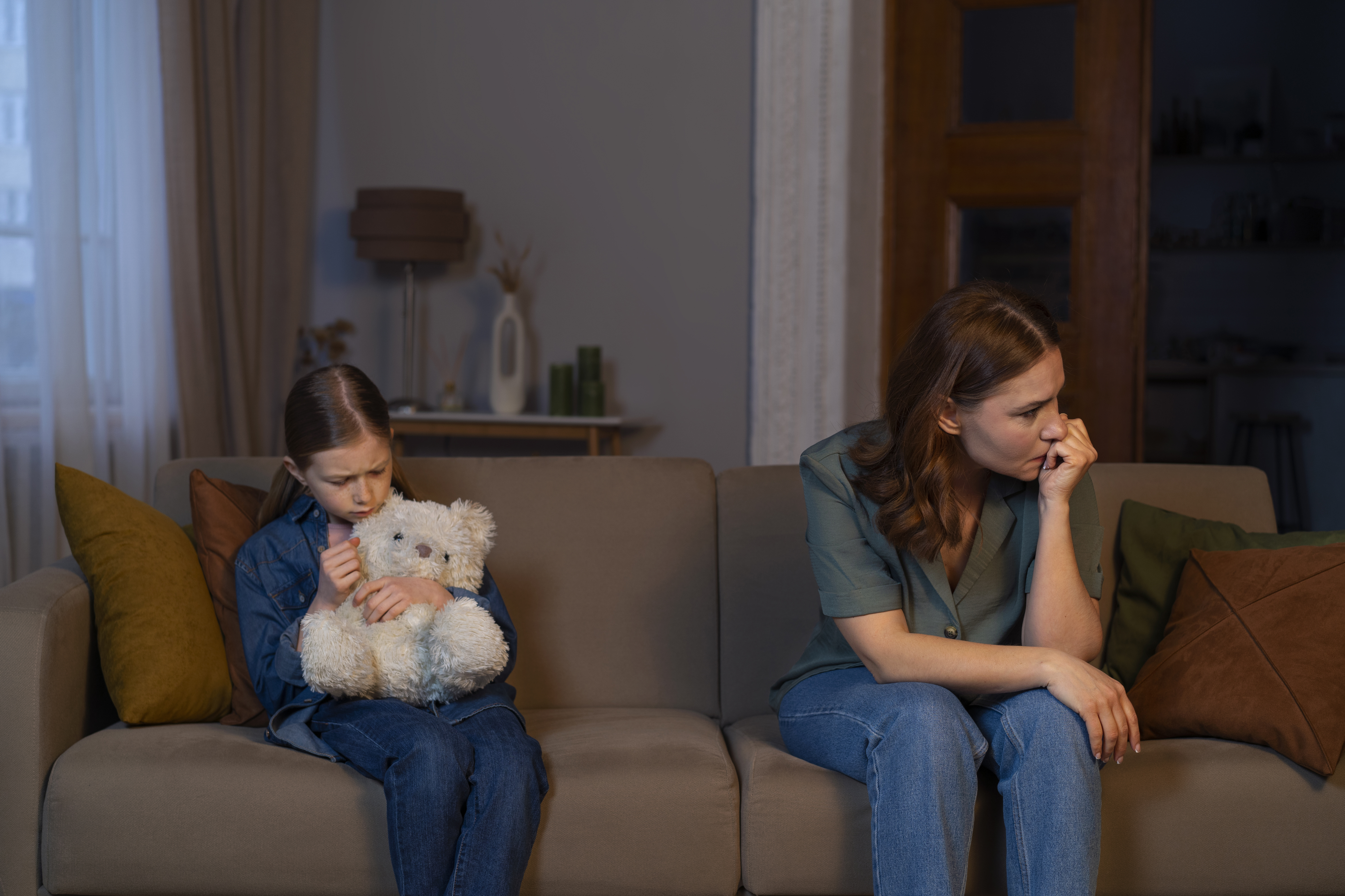 Parent and child sitting apart on a couch after a difficult moment